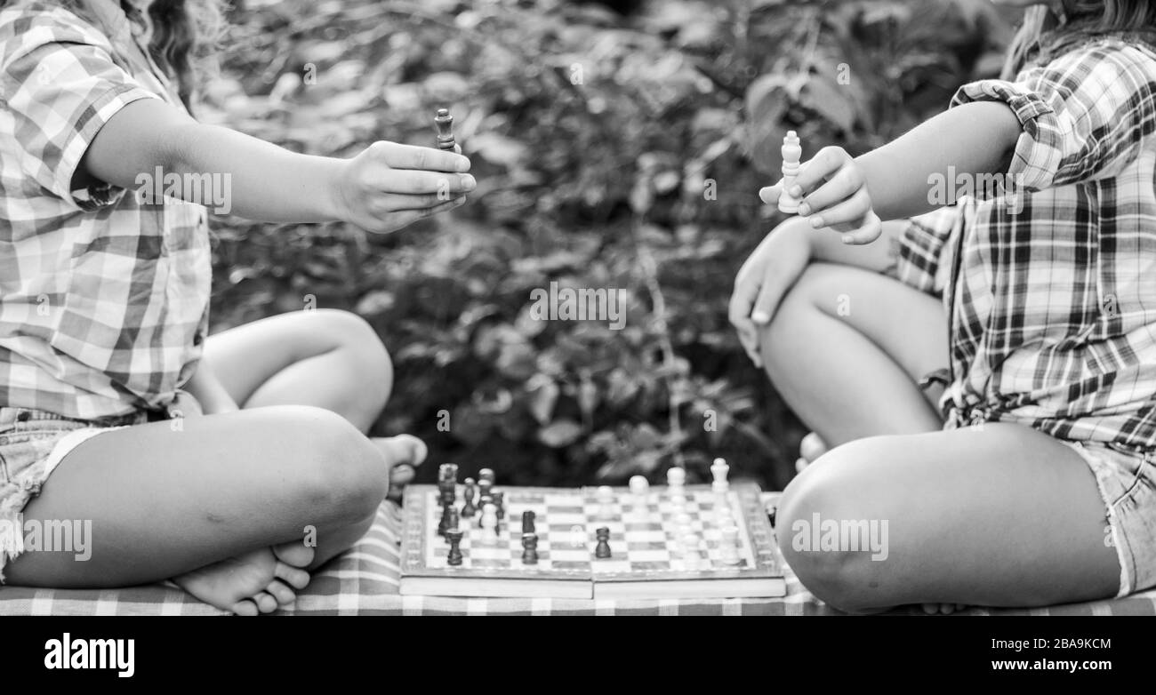 Jugar al ajedrez. Hermanas jugando al ajedrez. Los niños juegan al ajedrez al aire libre la naturaleza de fondo. Concepto de deporte y pasatiempo. El concepto de estrategia. El desarrollo cognitivo. Juego intelectual. La toma de decisiones. Los niños inteligentes. Foto de stock