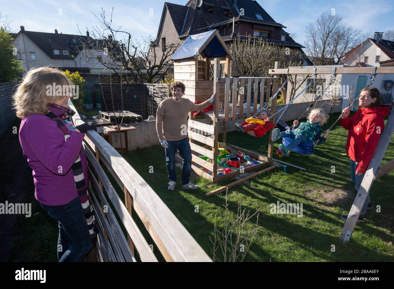 Distanciamiento social: Una abuela (izquierda) vino a una valla de jardín durante la pandemia del coronavirus para visitar a sus dos nietos mientras mantenía cierta distancia Foto de stock