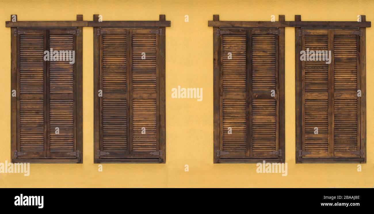 Persianas rústicas de madera marrón con fondo amarillo antiguo de la pared  de piedra Fotografía de stock - Alamy