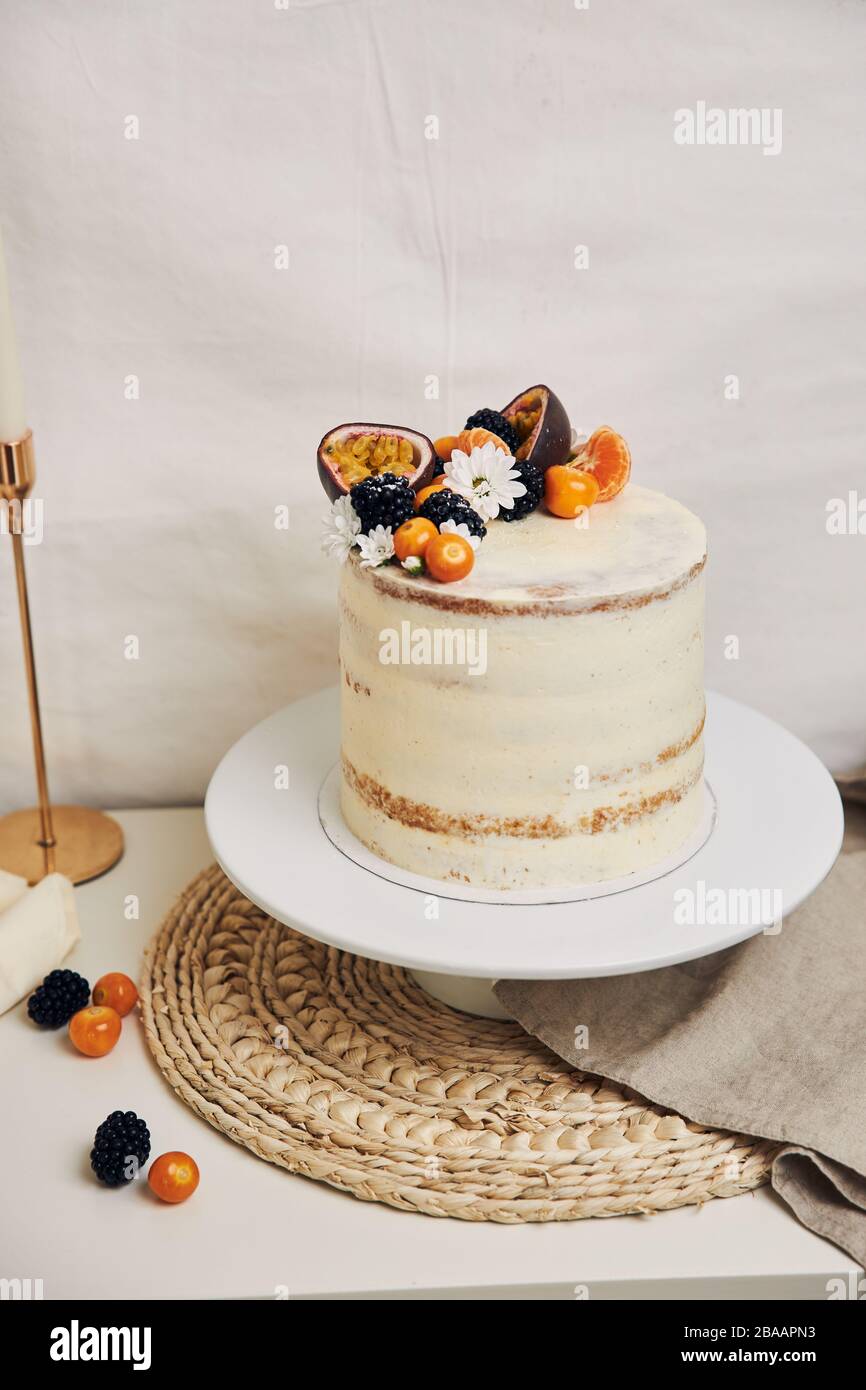 Tiro vertical de un pastel blanco con bayas y pasionfruits detrás de un  fondo blanco Fotografía de stock - Alamy