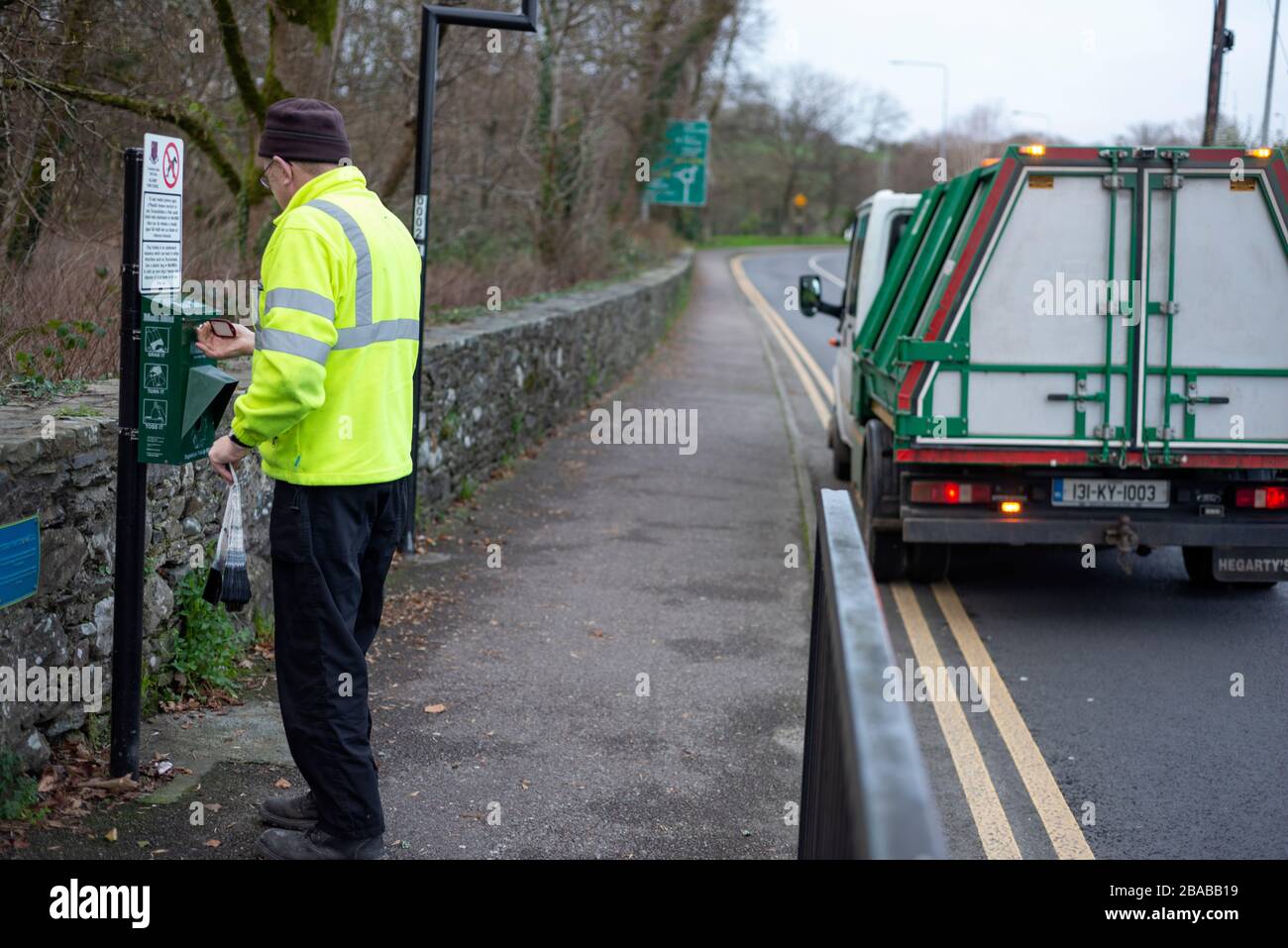 Trabajador del Consejo ocupado en el trabajo de mantenimiento de la estación Mutt Mitt para bolsas de desechos de perros degradables. Dispensador Mutt Mitt en Killarney, condado de Kerry, Irlanda Foto de stock