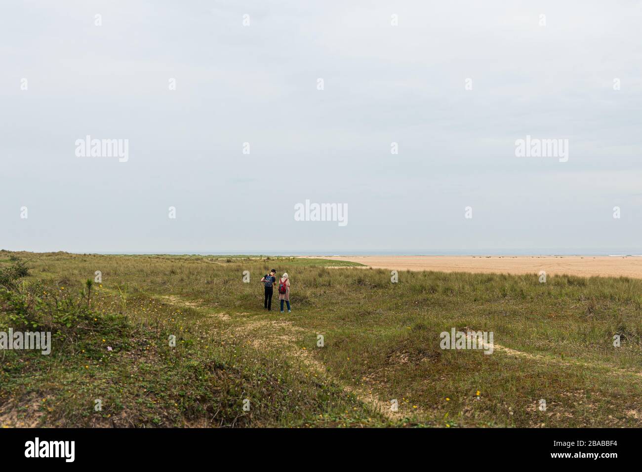 2 personas caminando por la costa de Norfolk Foto de stock