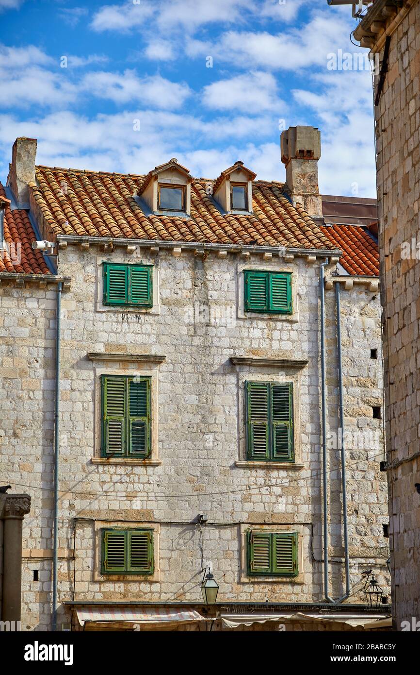 Fachada tradicional de piedra, techo de baldosas de arcilla y persianas de madera verde en el casco antiguo de Dubrovnik, Croacia Foto de stock