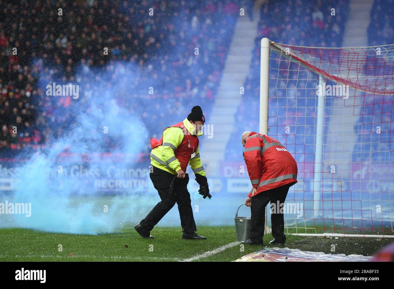 Los azafatas recuperan una bomba de humo lanzada en el campo por los fans de Blackburn Rovers Foto de stock