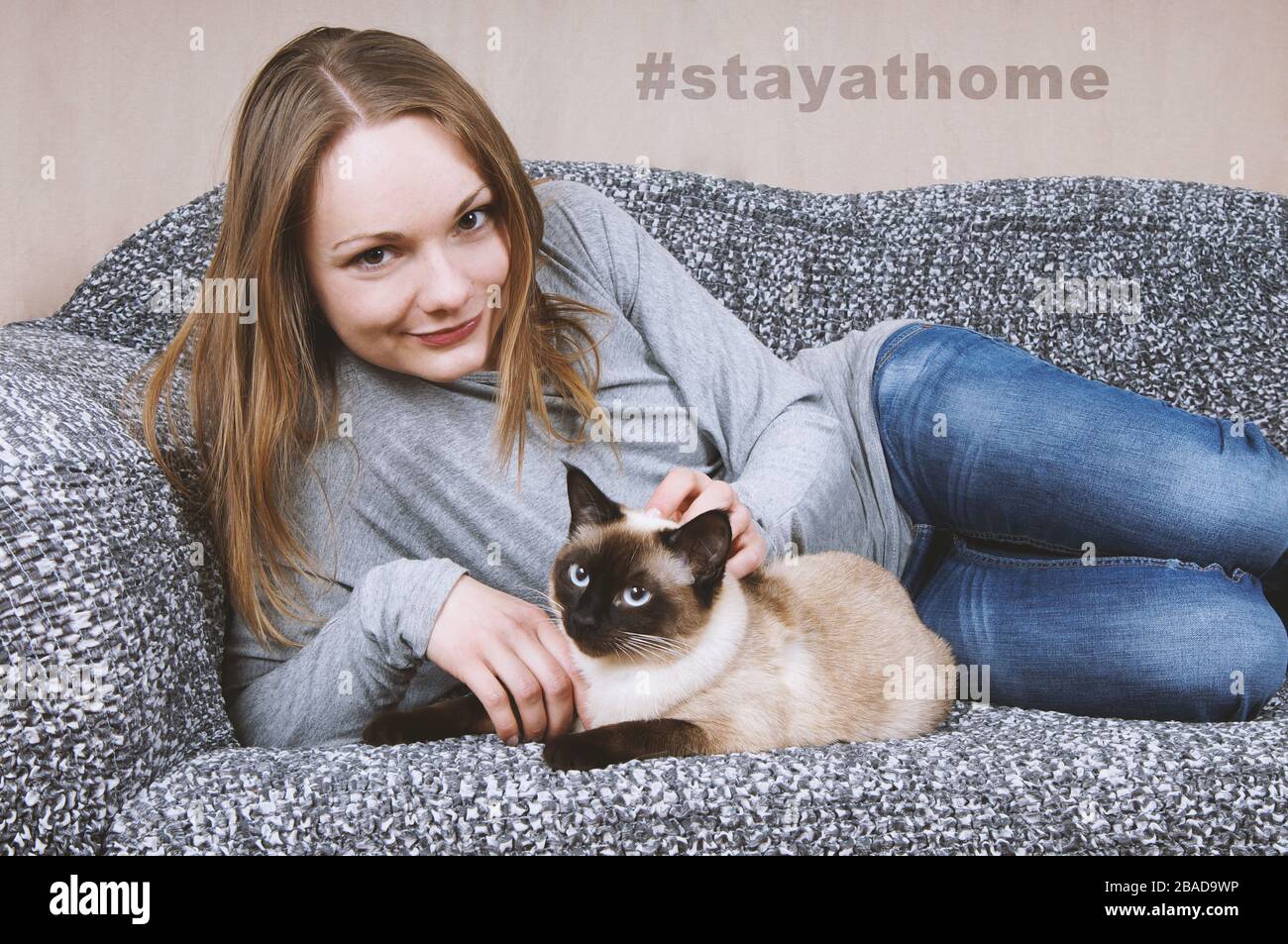 mujer joven que se queda en casa con gato como medida de distanciamiento  social durante la crisis de la corona - hashtag stayathome Fotografía de  stock - Alamy