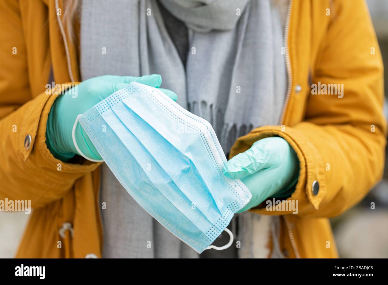 Imagen de cerca de la mujer que sostiene la máscara protectora, usando guantes debido a la pandemia del coronavirus Foto de stock
