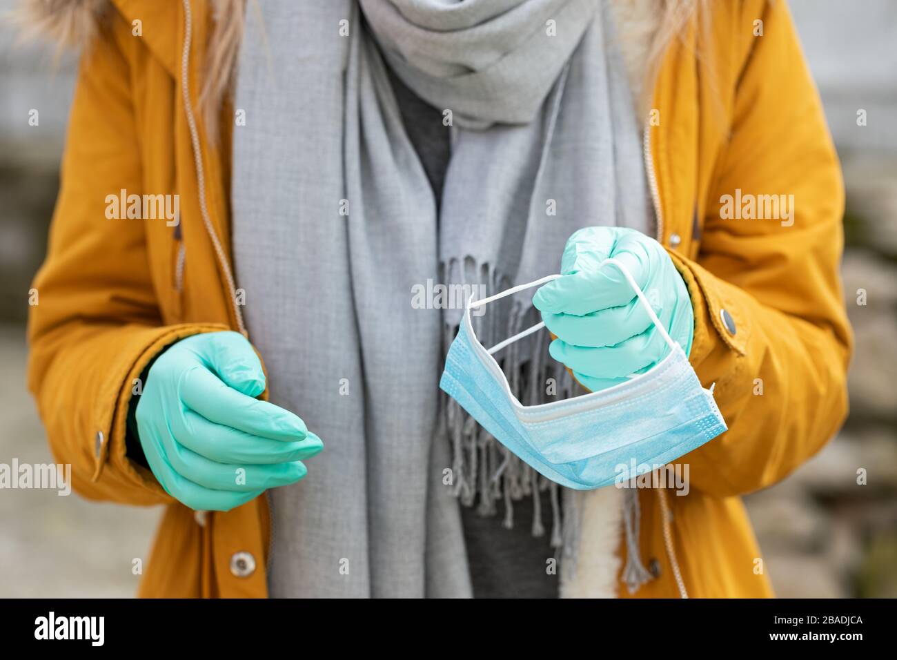 Imagen de cerca de la mujer que sostiene la máscara protectora, usando guantes debido a la pandemia del coronavirus Foto de stock