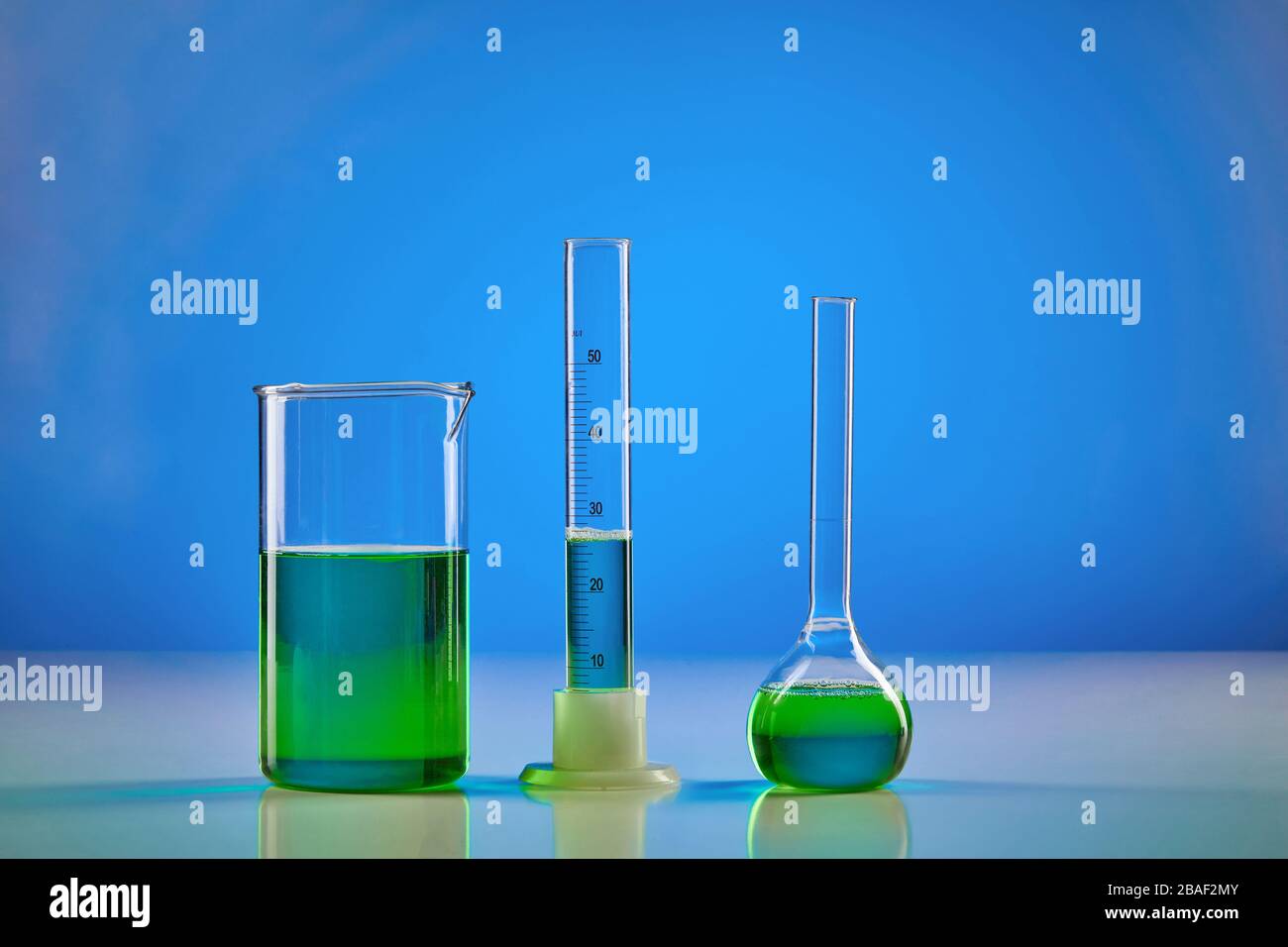 Reactivo químico verde en vaso de precipitado, matraz médico y probador,  fondo azul. Investigación de laboratorio del coronavirus. COVID pandémico  mundial Fotografía de stock - Alamy