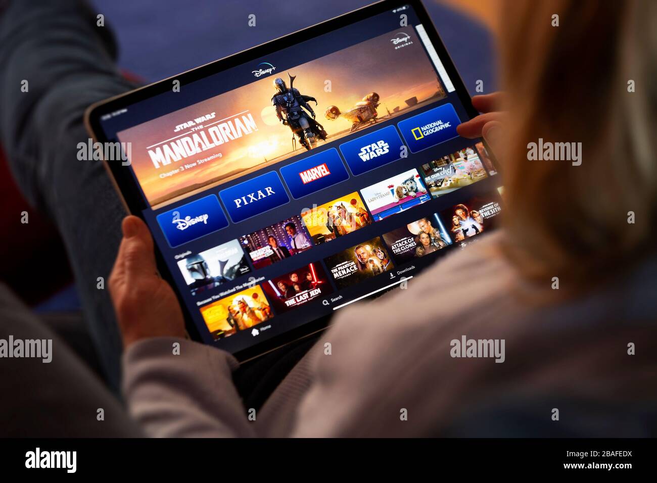 BATH, Reino Unido - 27 DE MARZO de 2020 : persona anónima mirando la aplicación Disney+ en un iPad de Apple. Foto de stock