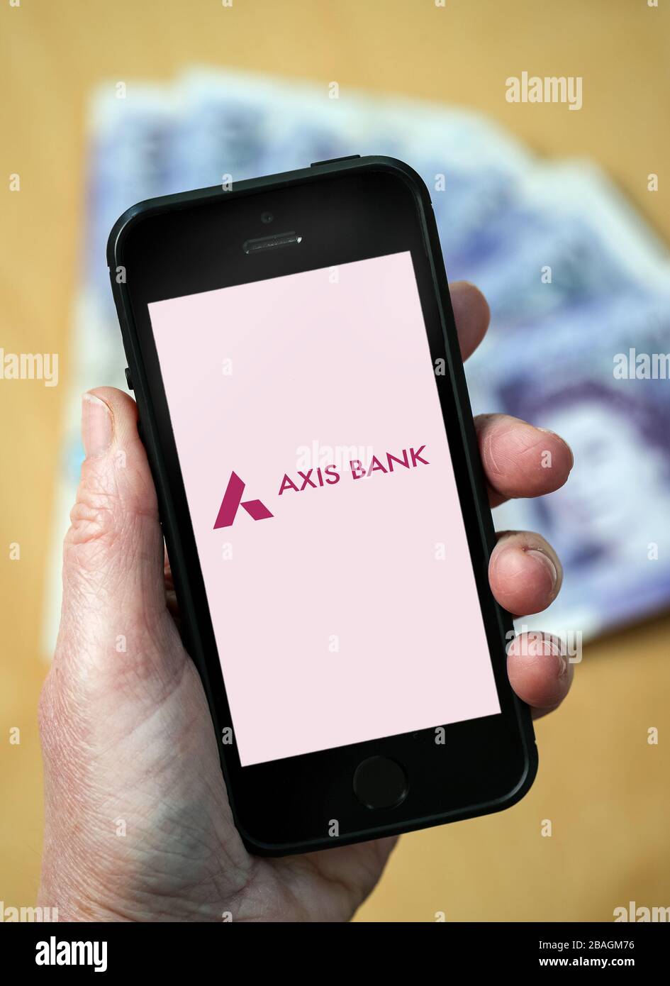 Una mujer que mira el logotipo de Axis Bank en un teléfono móvil. (Sólo para uso editorial) Foto de stock