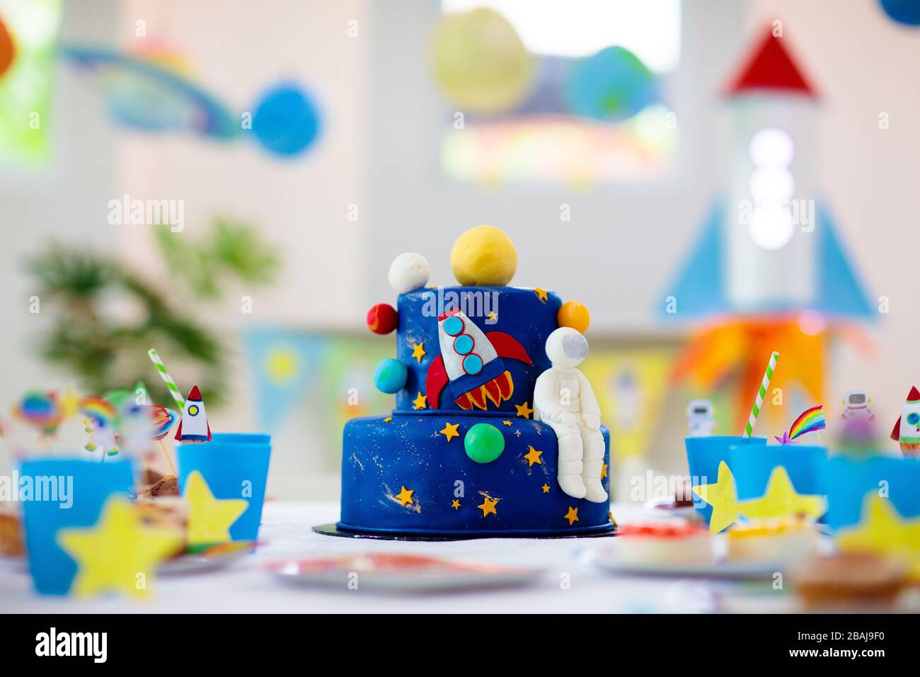 Fiesta de cumpleaños con tema de espacio para niños con pastel y cupcakes.  Cohete, planeta del sistema solar y decoración de astronauta para el evento  infantil. Ajuste de mesa para poco Fotografía