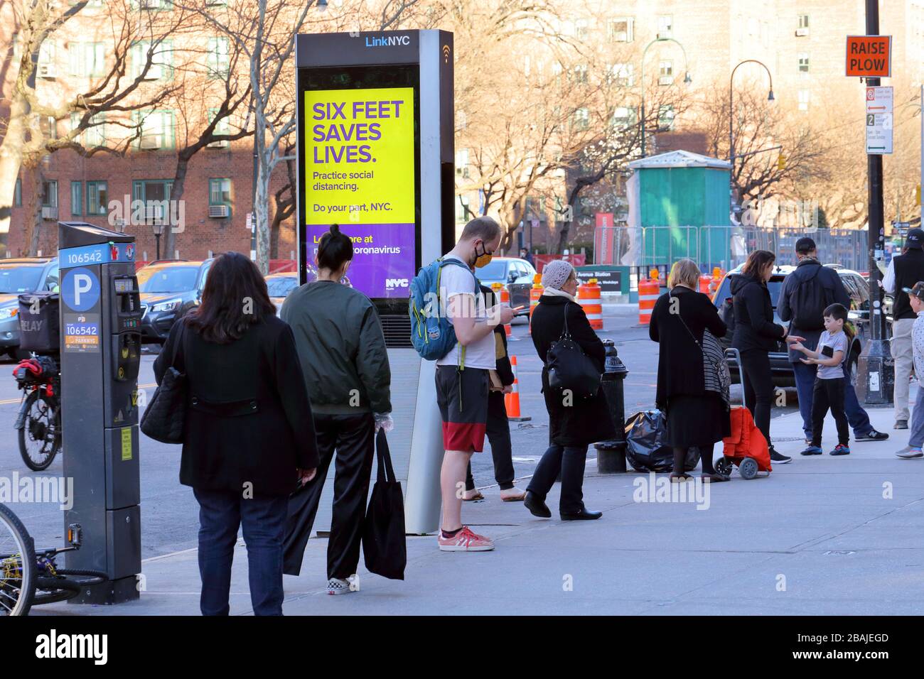 Nueva York, NY, 27 de marzo de 2020. Neoyorquinos practicando distanciamiento social mientras hacen cola para entrar en un supermercado... VEA MÁS INFORMACIÓN PARA VER EL TÍTULO COMPLETO Foto de stock