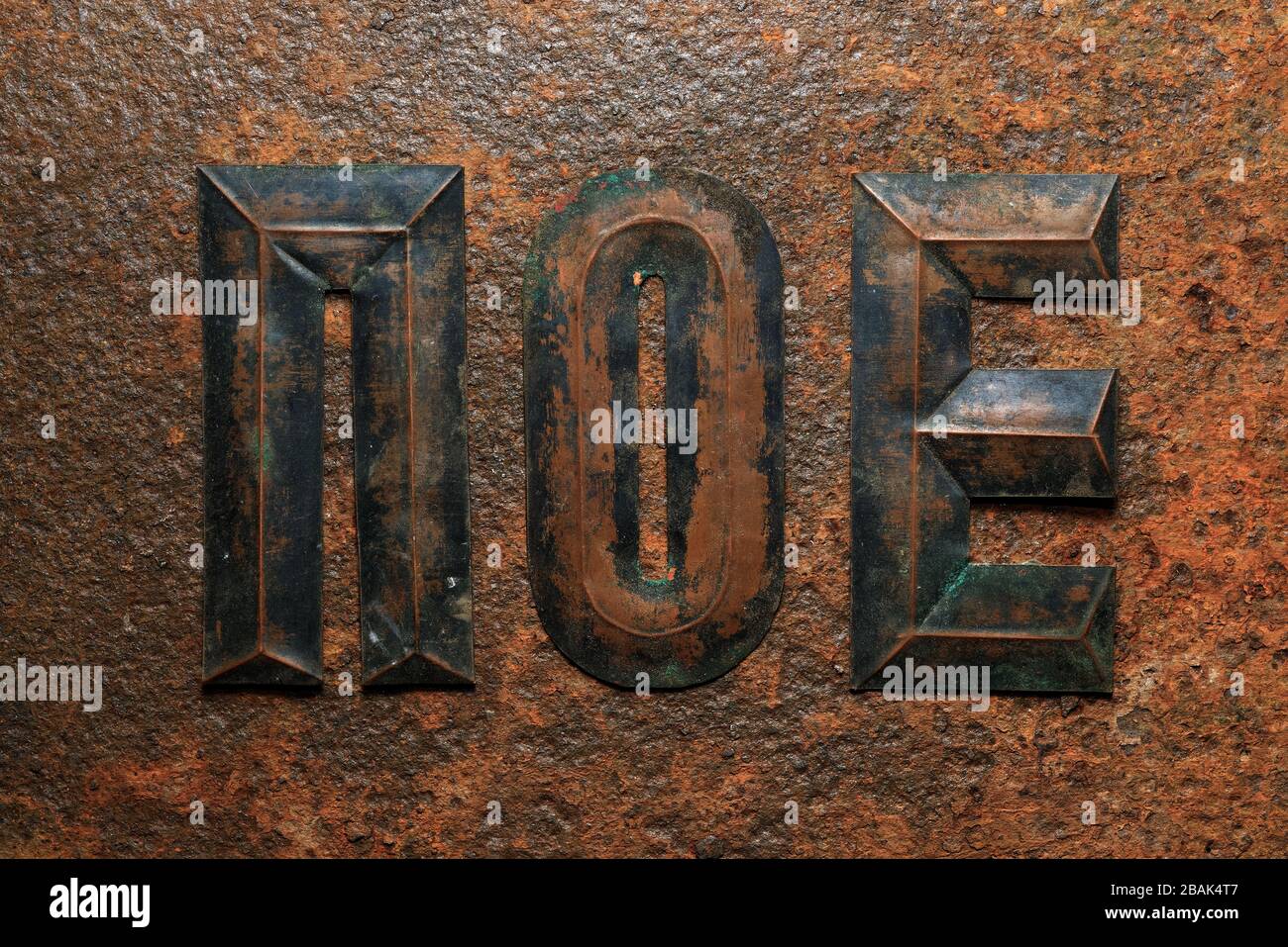 Fondos y texturas: Grupo de letras cirílicas de cobre en relieve envejecidas sobre una superficie de metal oxidado muy corroída Foto de stock