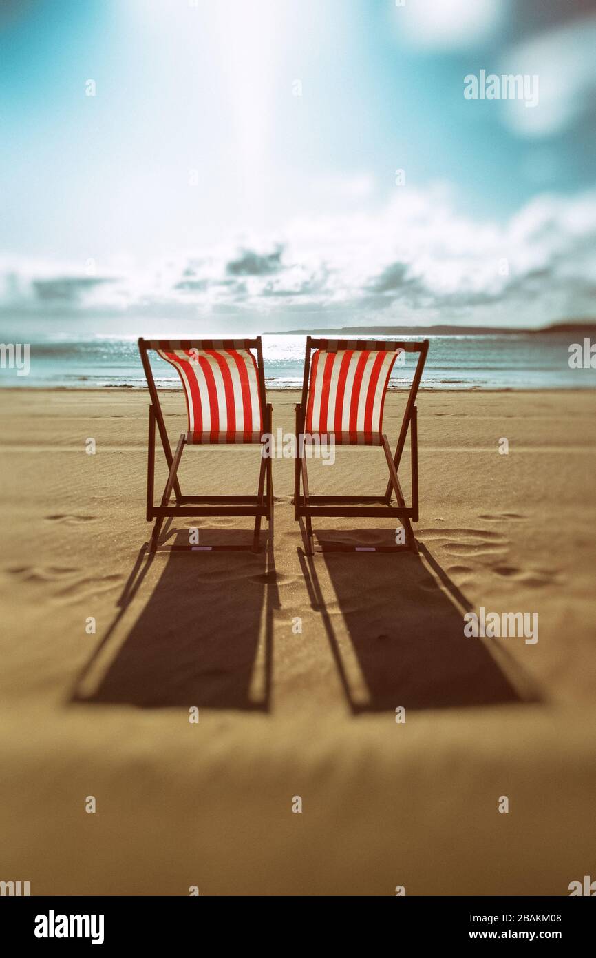 Dos solitarias tumbonas rojas y blancas en una playa desierta Foto de stock