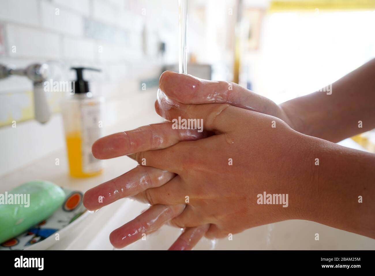 Lavarse las manos del niño con jabón bajo el grifo de la cocina Foto de stock