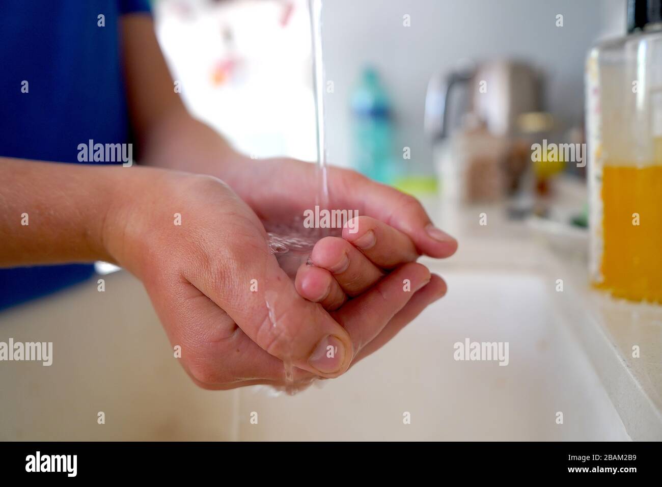 Lavarse las manos del niño con jabón bajo el grifo de la cocina Foto de stock