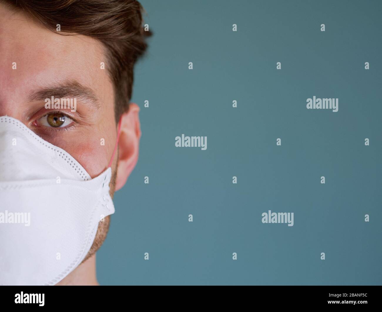 Primer plano de un hombre caucásico cara con mono divertido máscara de protección de la cara con ojos y cabello marrón, desde nuevo brote de coronavirus. Foto de stock