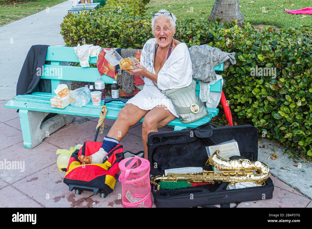 Miami Beach Florida,Lummus Park,mujer sin hogar,mujeres,ancianos ciudadanos,vagabundos,banco,saxofón,instrumento musical,instrumentos,FL11033104 Foto de stock