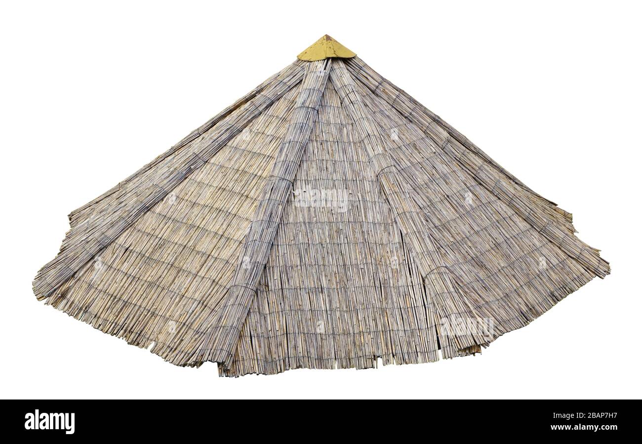El techo del granero del pueblo o sombrilla de playa está hecho de haces de caña seca. Aislado sobre blanco Foto de stock