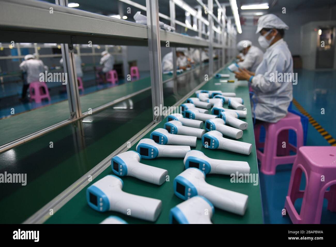 Ding'an, China. 28 de marzo de 2020. Los trabajadores ensamblan termómetros  para frente en una fábrica del condado de Ding'an, en la provincia de  Hainan, al sur de China, el 28 de