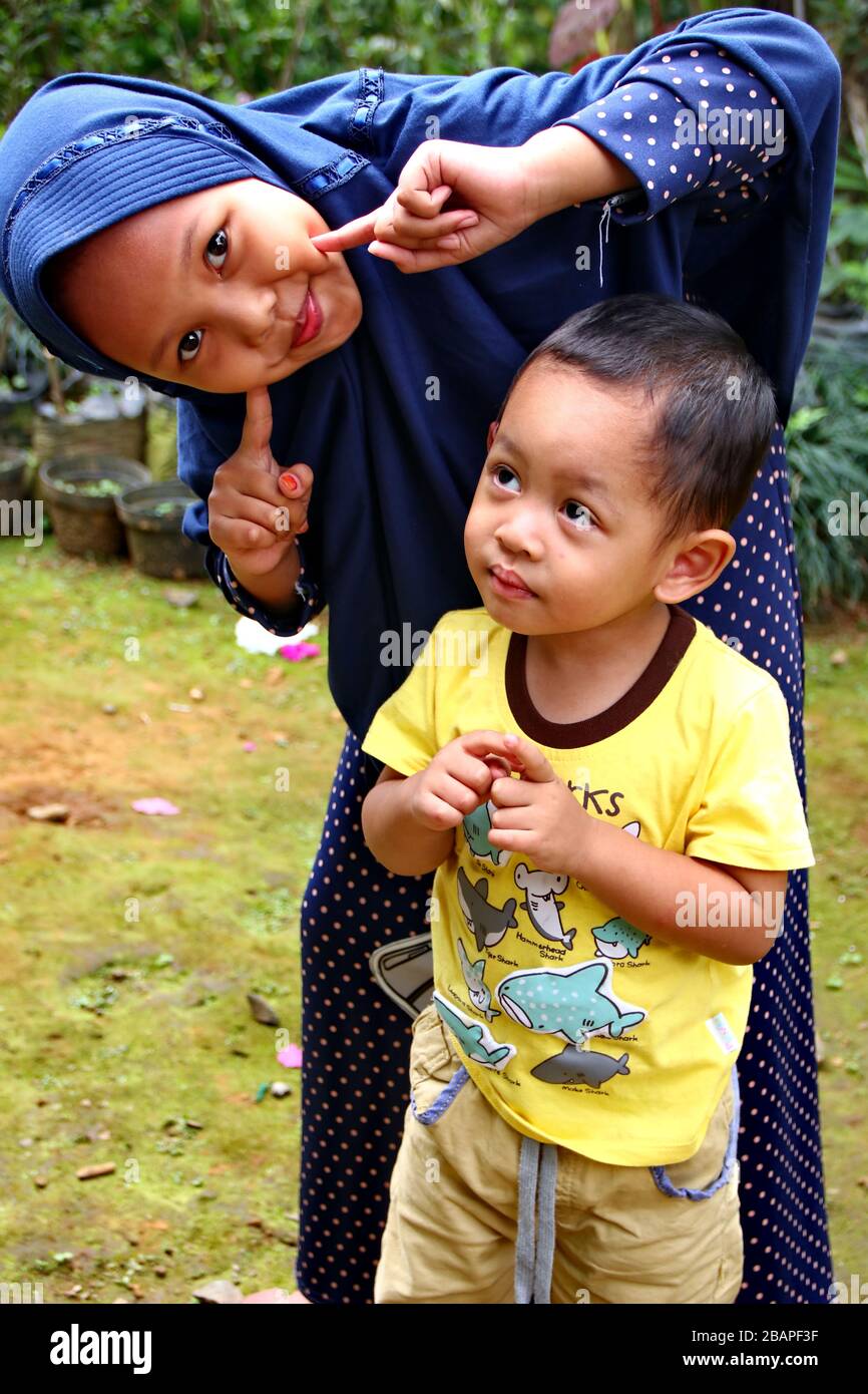 Imagen borrosa sin enfoque niña jugando con su hermano menor en el parque, Batang Indonesia, Foto de stock