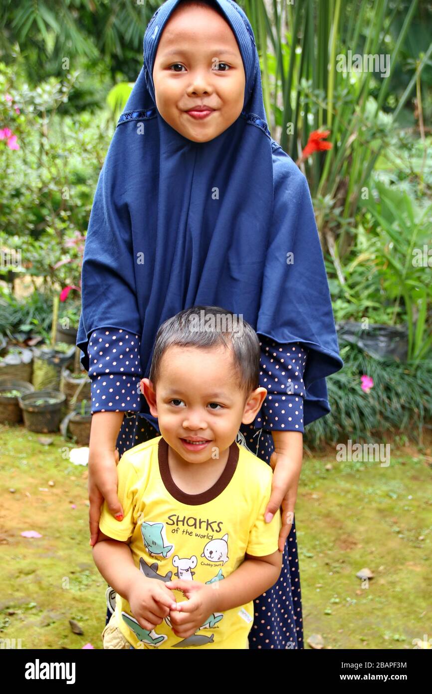 Imagen borrosa sin enfoque niña jugando con su hermano menor en el parque, Batang Indonesia, Foto de stock