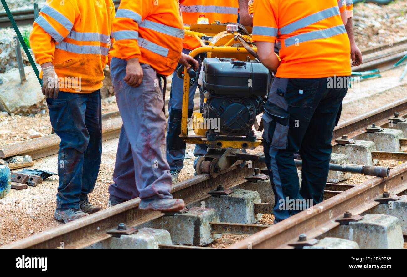 Trabajadores del ferrocarril que están atornillando el ferrocarril. Trabajador de detalle con llave de apriete mecánica Foto de stock