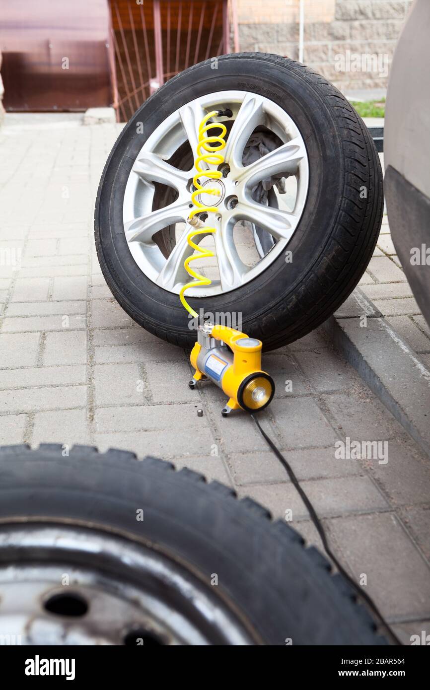 Inflado de la rueda del vehículo desmontada después de la reparación,  inflador de neumáticos amarillo conectado con manguera para el trabajo  Fotografía de stock - Alamy