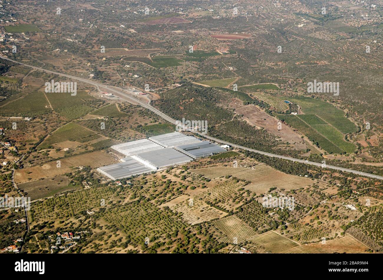 Vista aérea de invernaderos operados por la empresa Hubel en Fazenda Nova, en la región de Faro, Portugal la carretera A22 atraviesa el paisaje. Foto de stock