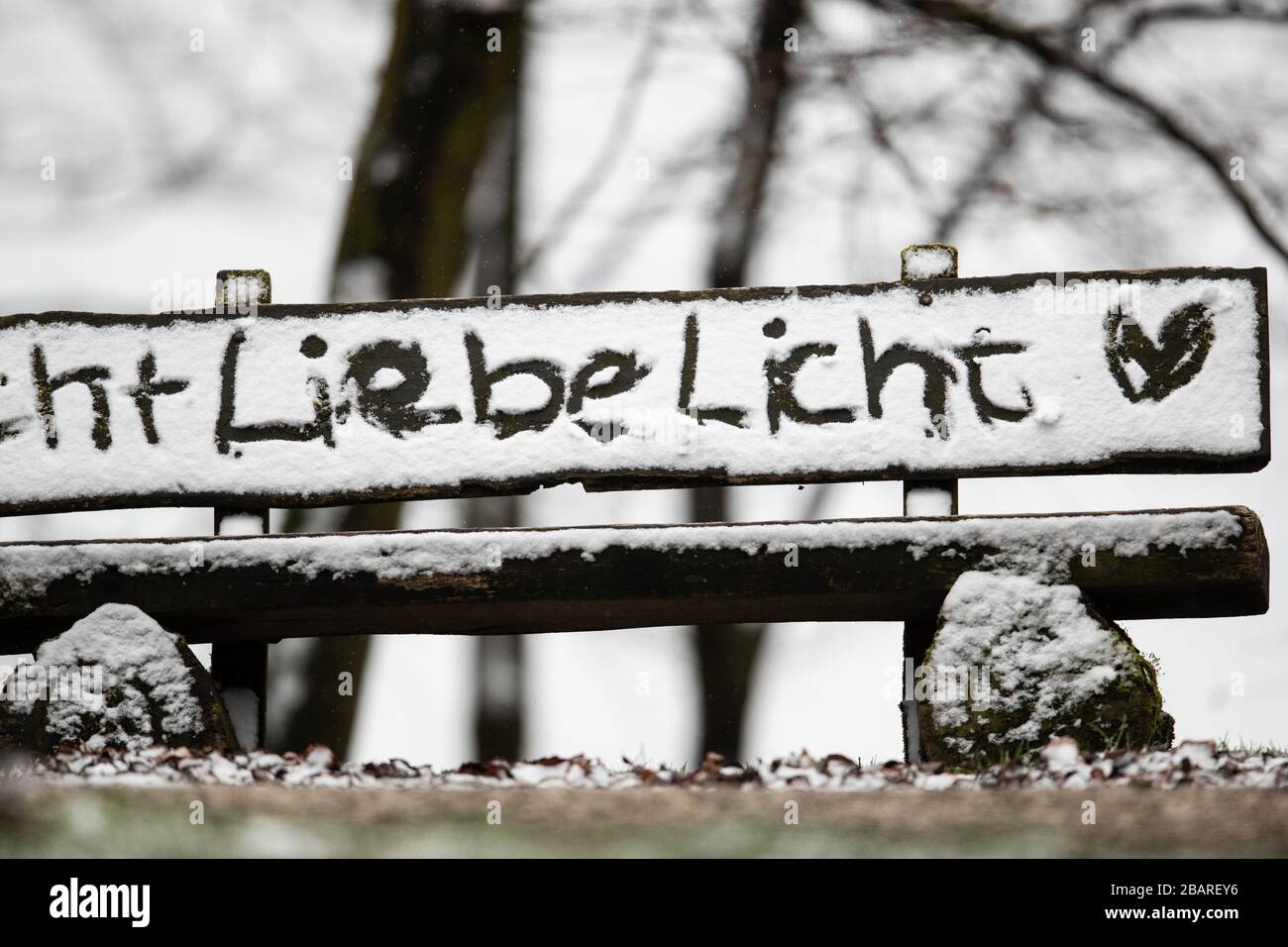 Bielefeld, Alemania. 29 de marzo de 2020. Las palabras "Luz de oído" y un corazón fueron pintados en la nieve en el respaldo de un banco, que se alza en un sendero de senderismo en el bosque de Teutoburg. Después del clima de primavera de los últimos días con temperaturas de dos dígitos, ha nevado en partes de Renania del Norte-Westfalia. Crédito: Friso Gentsch/dpa/Alamy Live News Foto de stock