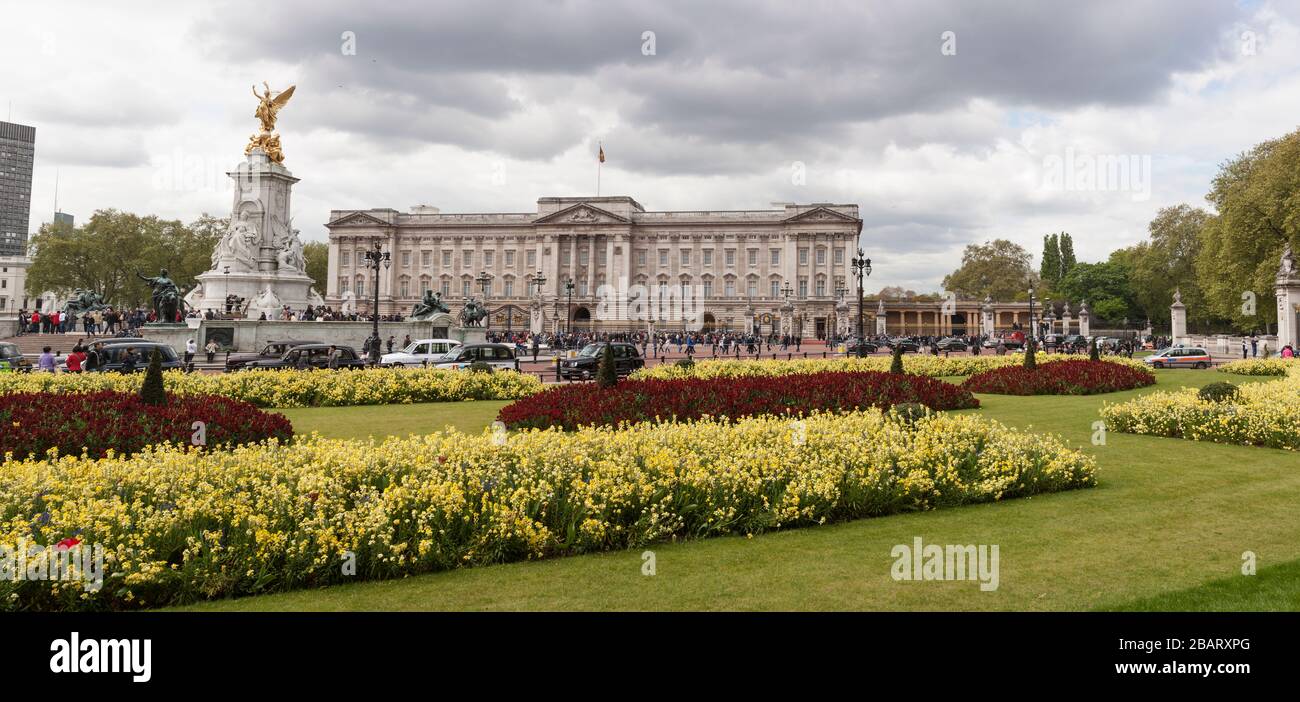 Palacio de Buckingham con jardines del Victoria Memorial: La fachada frontal del Palacio de Buckingham con el Victoria Memorial y flores de primavera. Foto de stock