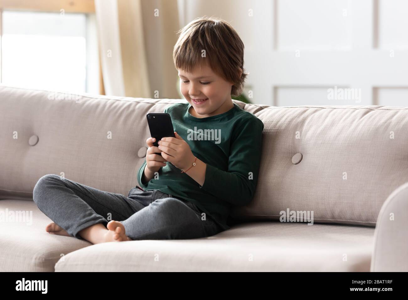 Sonriendo niño pequeño preescolar jugar juego en línea. Foto de stock