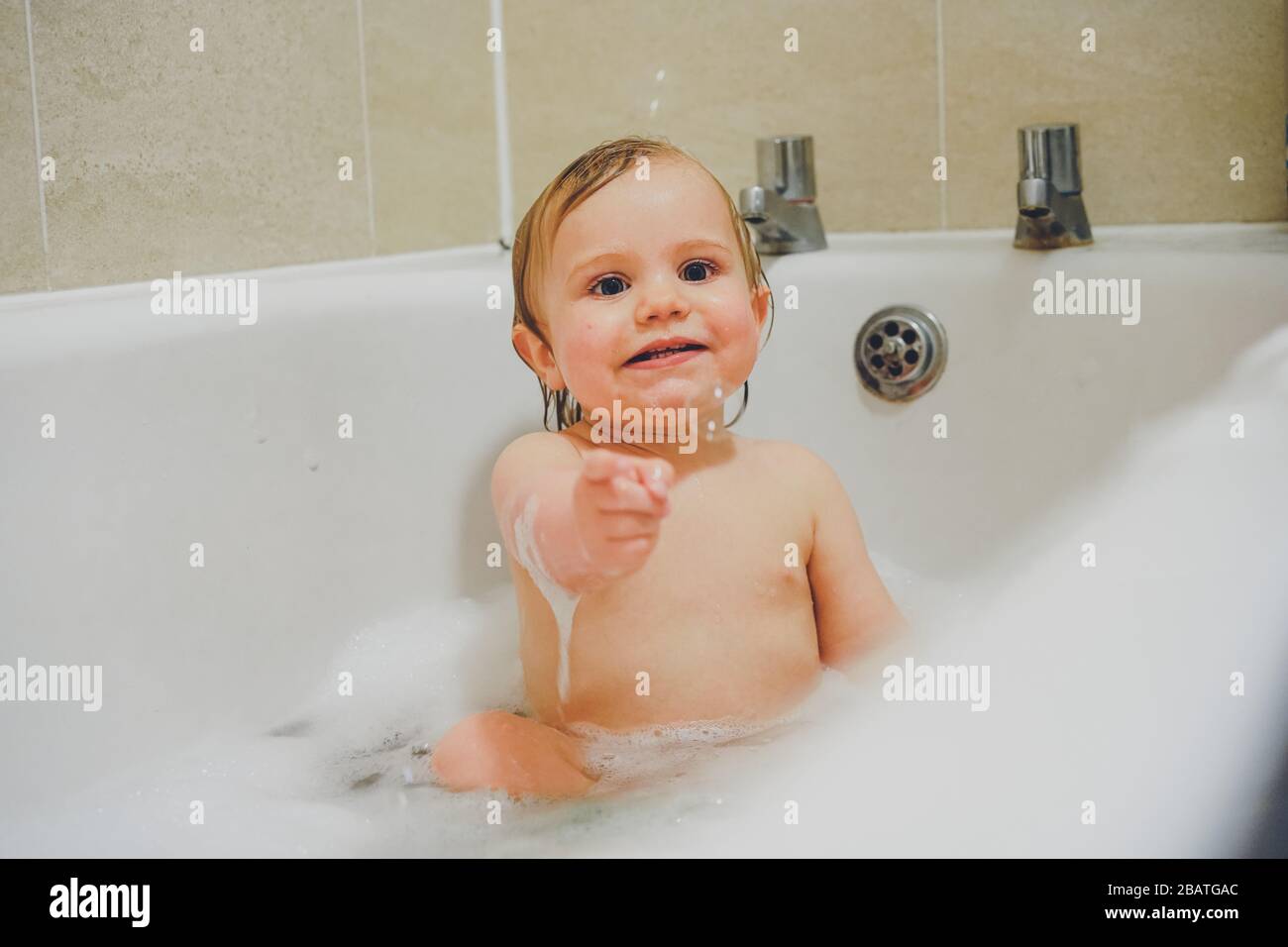 Niño jugando en el baño con burbujas Foto de stock