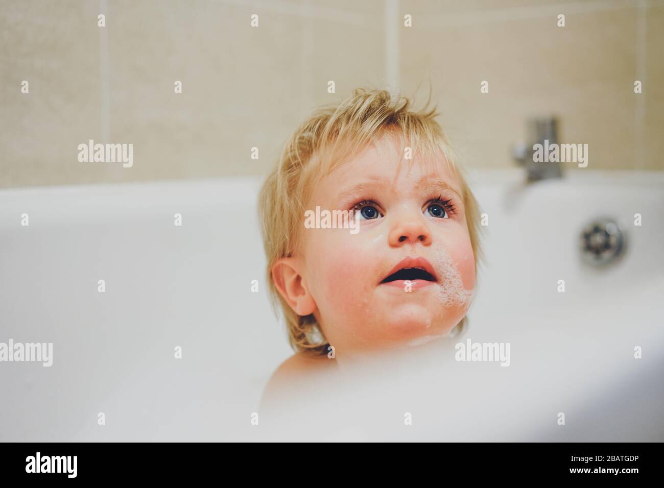 Niño jugando en el baño con burbujas Foto de stock