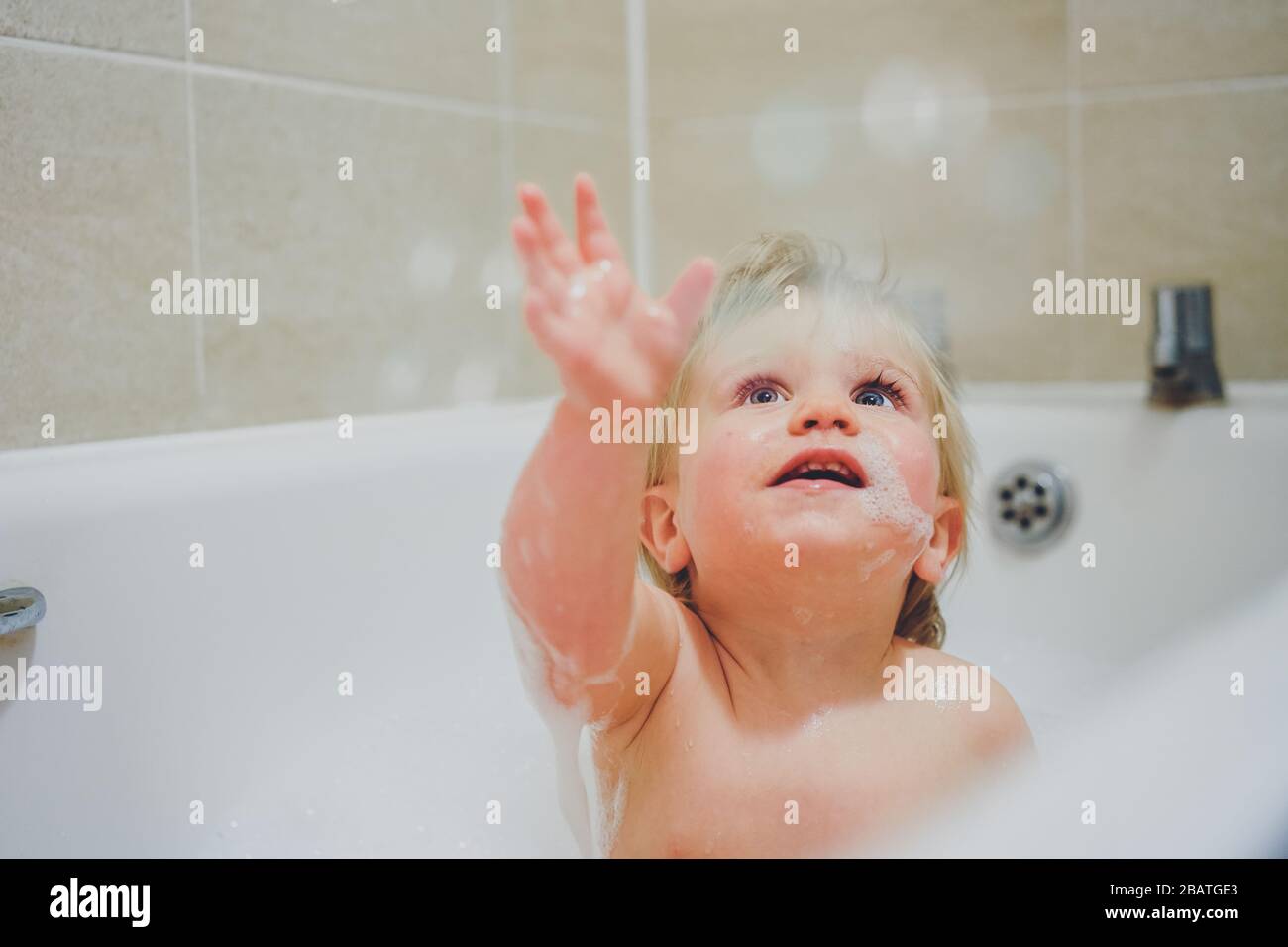 Niño jugando en el baño con burbujas Foto de stock