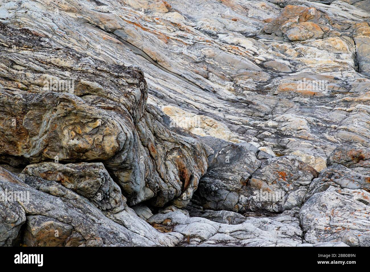 Cerca de una roca metamórfica que parece que era un fluido líquido con sus muchas capas en la costa rocosa del Mar Báltico en Suecia. Foto de stock