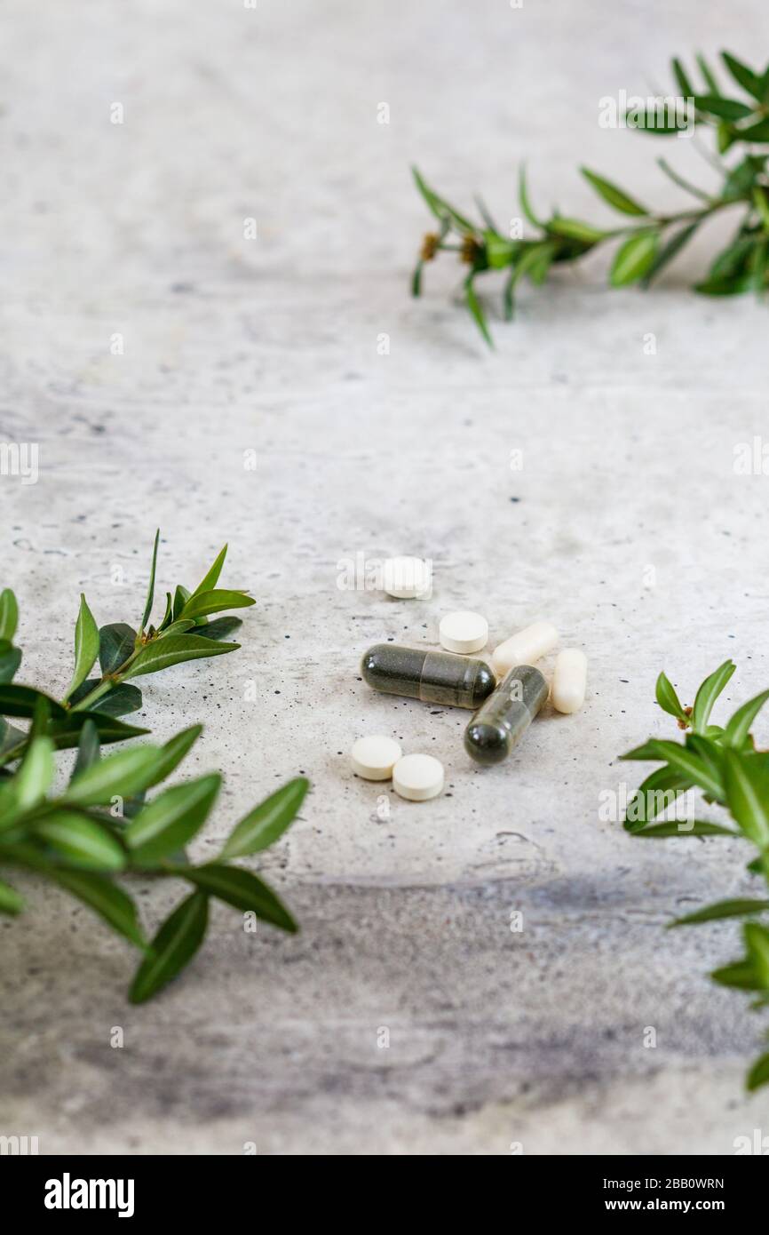 Cápsulas y tabletas de diferentes vitaminas sobre fondo gris. Concepto de bienestar. Foto de stock