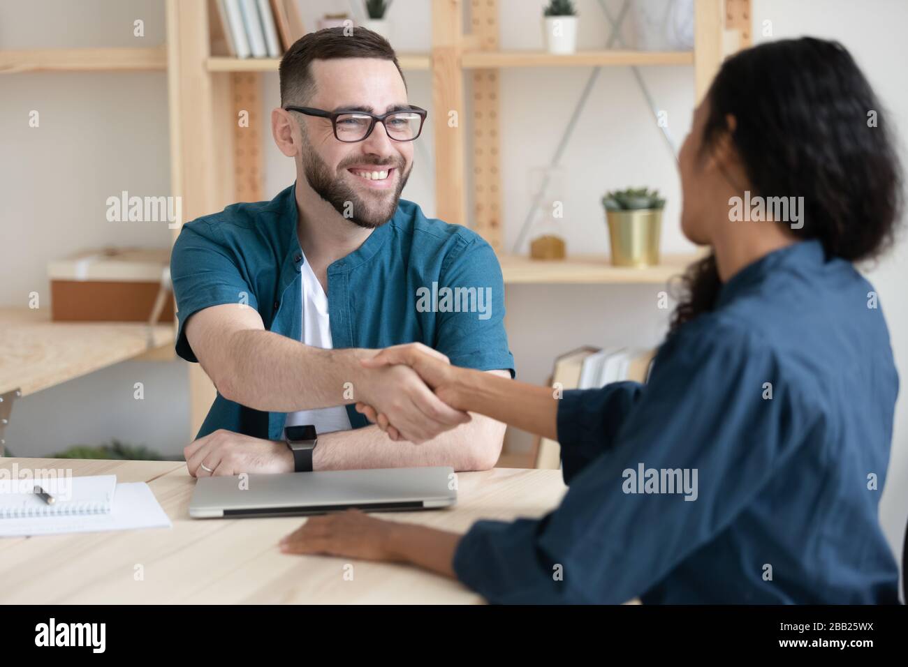 Hombre sonriente patrón apretón de manos mujer candidato de trabajo en la reunión Foto de stock