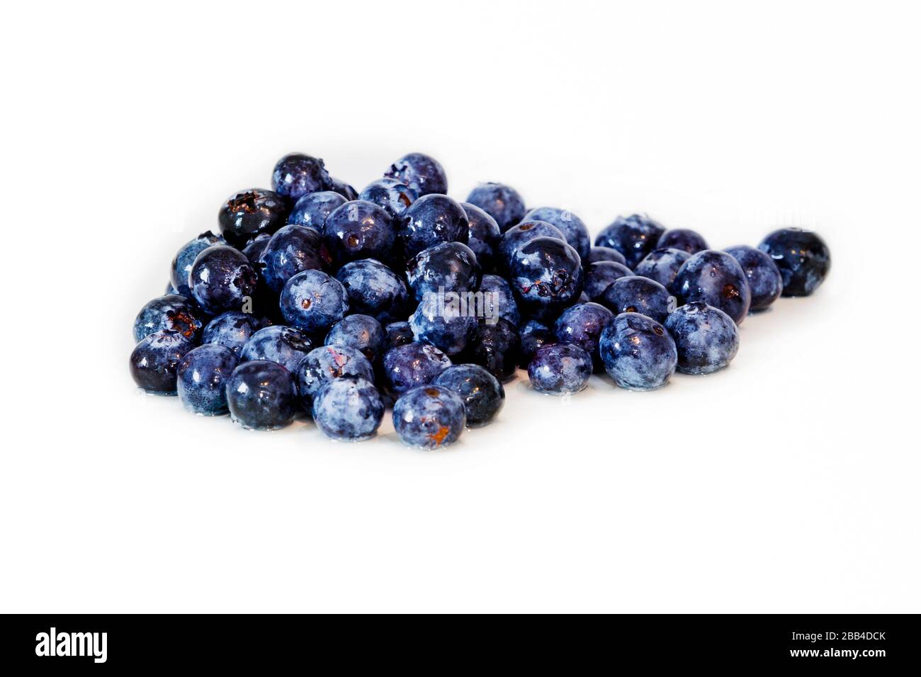 Deliciosas frutas de temporada, varios arándanos sueltos, mezclados en una parte superior blanca sobre un fondo blanco. Un perfecto desayuno o aperitivo saludable. Foto de stock