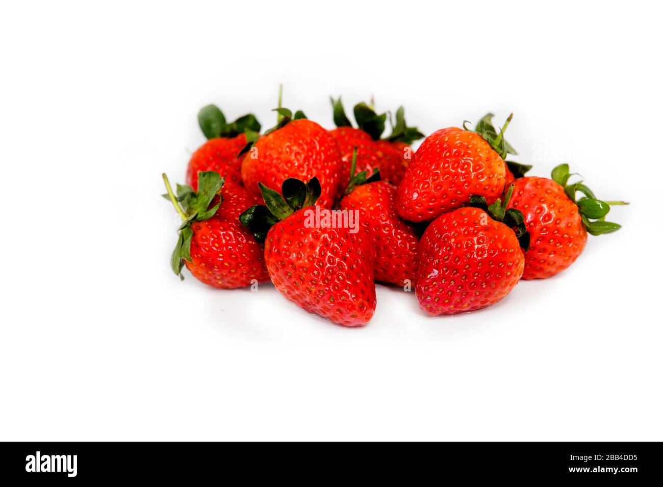 Deliciosas frutas de temporada, varias fresas sueltas, mezcladas en una parte superior blanca sobre un fondo blanco. Un perfecto desayuno o aperitivo saludable. Foto de stock