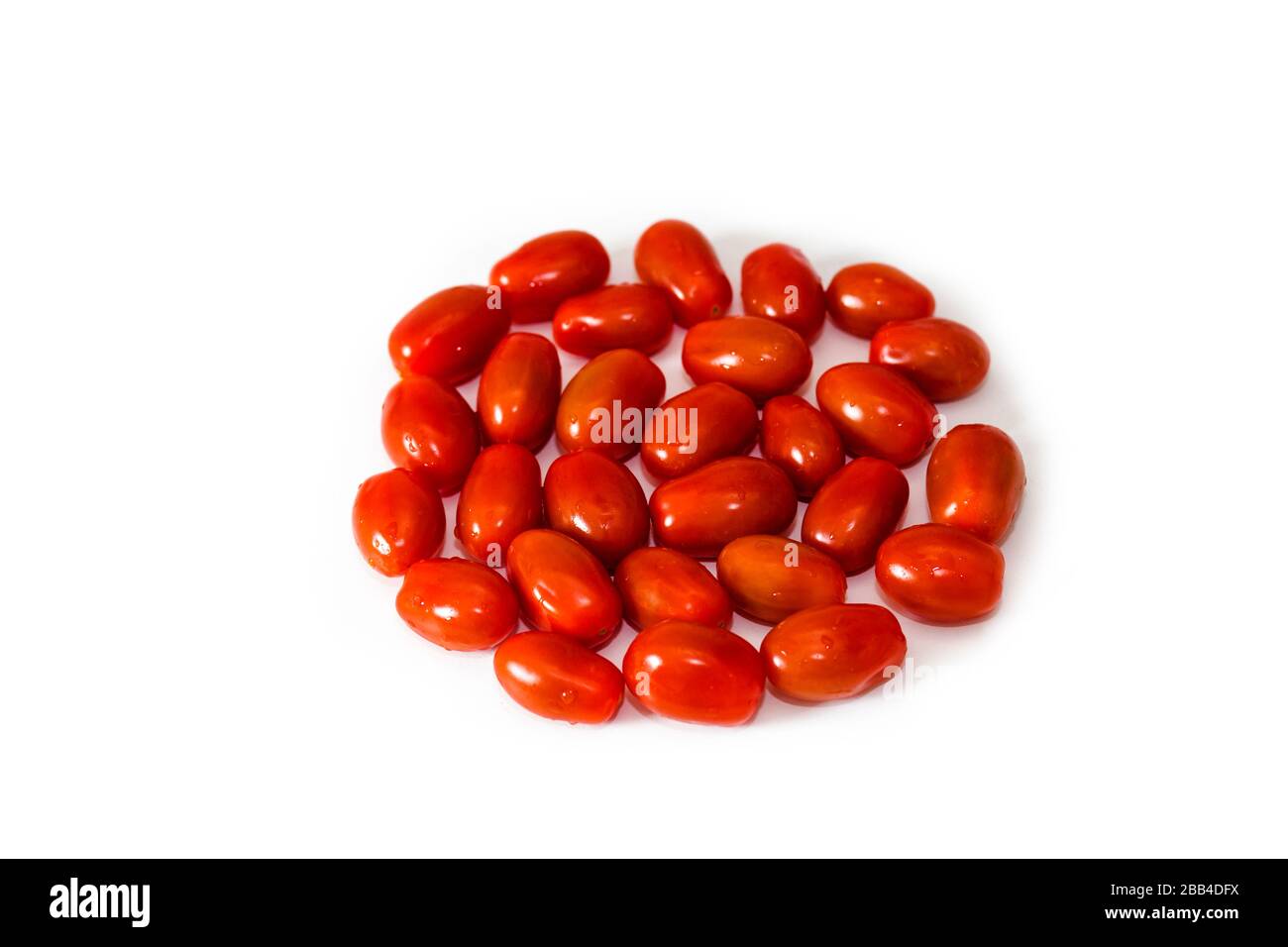 Deliciosos tomates ciruelos, mezclados en círculo. Grabado desde arriba. Con fondo blanco. Una opción perfecta para un aperitivo orgánico saludable, durante toda la temporada Foto de stock