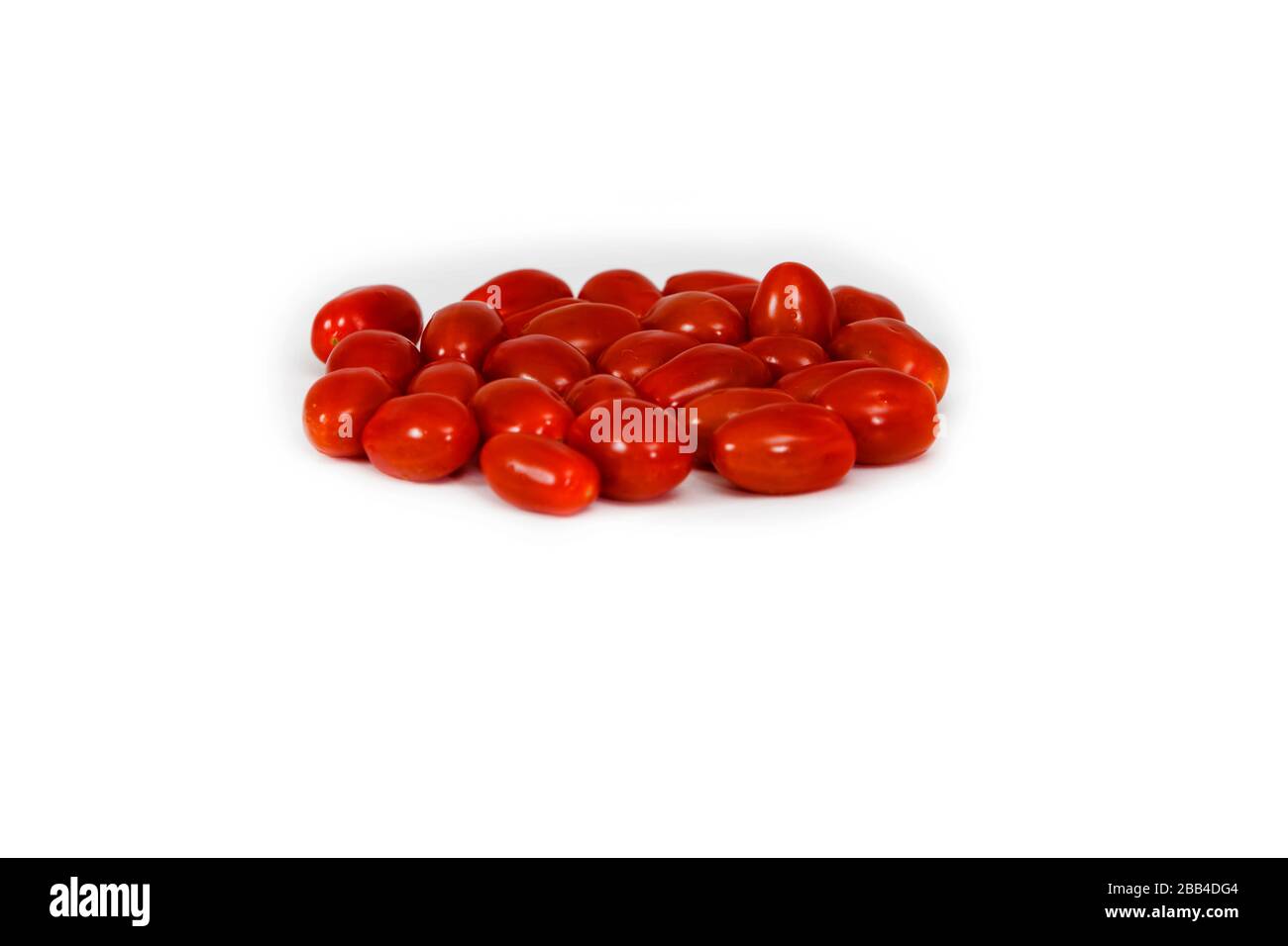 Deliciosos tomates ciruelos, mezclados en círculo. Grabado desde arriba. Con fondo blanco. Una opción perfecta para un aperitivo orgánico saludable, durante toda la temporada Foto de stock
