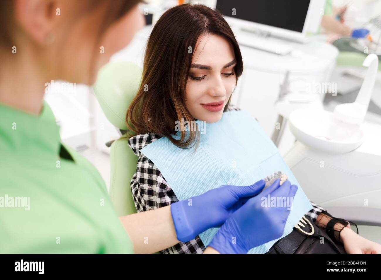 El dentista muestra al paciente un modelo de dientes Foto de stock