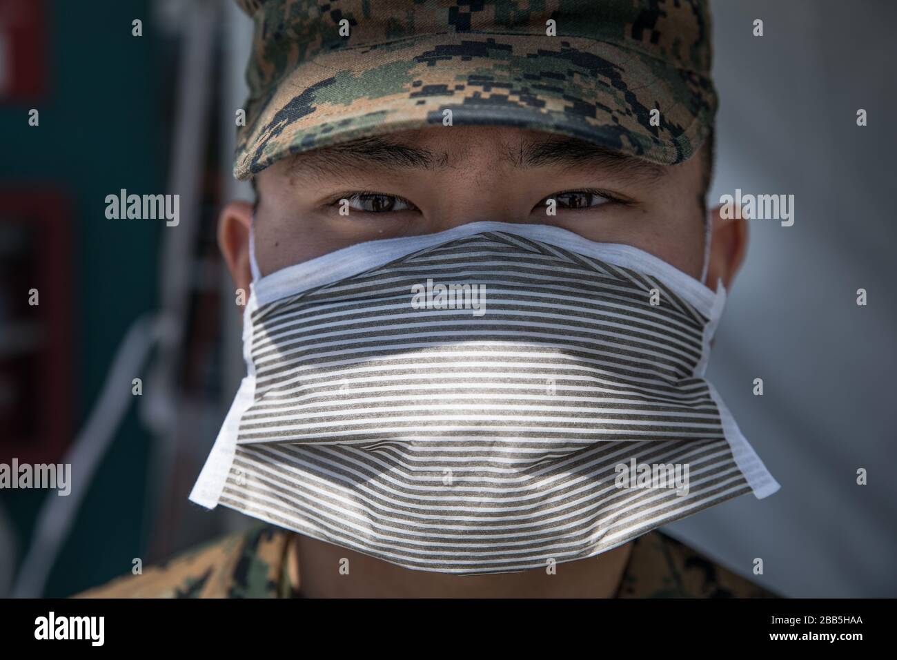 Los Ángeles, Estados Unidos de América. 29 de marzo de 2020. PFC. Marino EE.UU. Brandon Shim, usando equipo de protección personal, protege el puesto de control del buque del hospital Military Sealift Command USNS Mercy mientras comienza a tratar a los pacientes en apoyo de la pandemia COVID-19 el 29 de marzo de 2020 en los Ángeles, California. Crédito: Alexa Hernández/EE.UU Navy Photo/Alamy Live News Foto de stock