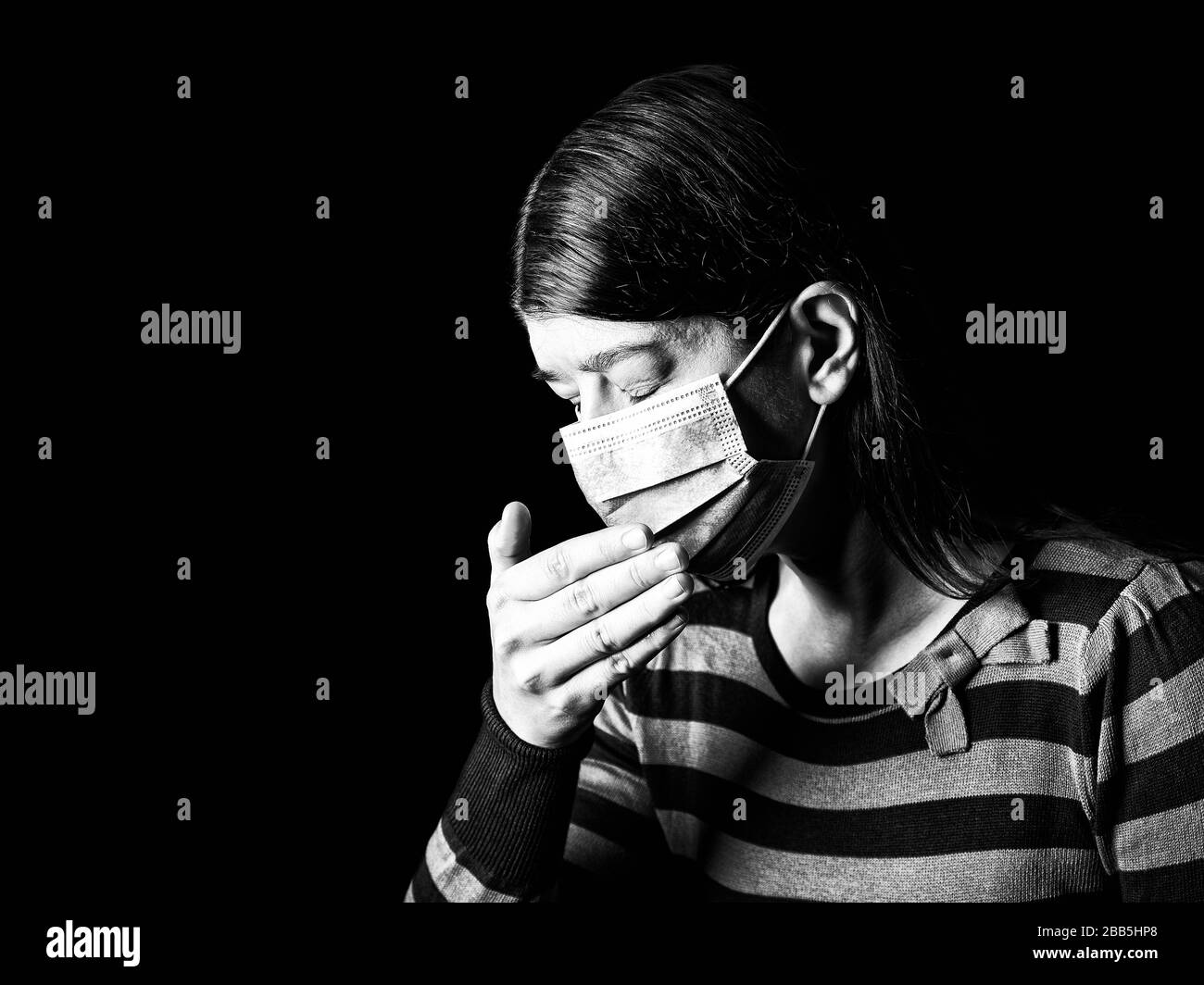 Mujer con mascarilla quirúrgica estornuda o tosiendo. Concepto de pandemia o epidemia y miedo, miedo o peligro. Protección contra riesgos biológicos como COVID-19 aka Coro Foto de stock