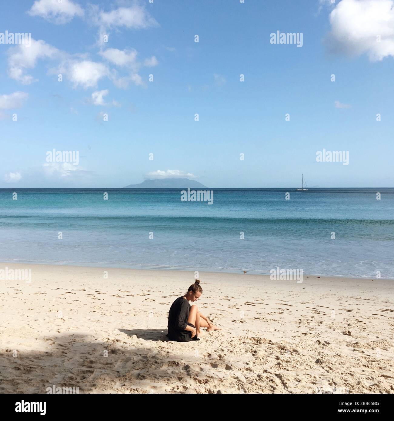 Mujer sentada en la playa, Seychelles Foto de stock