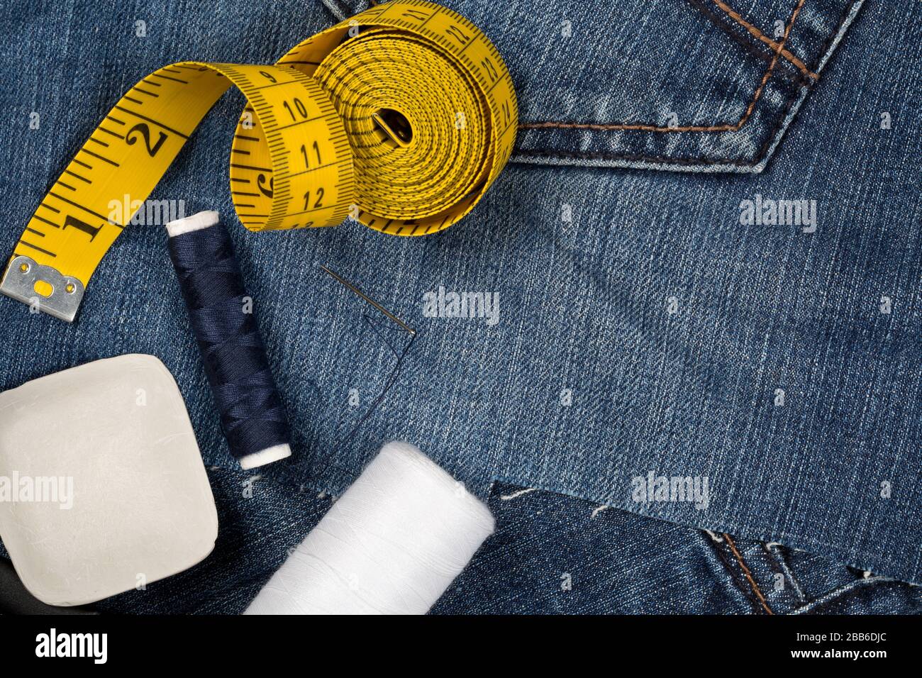 Pantalón de tela de algodón denim azul rasgado con herramientas de sastre:  Jeans estilo de reparación o de moda concepto, vista plana desde arriba con  espacio para copiar Fotografía de stock -