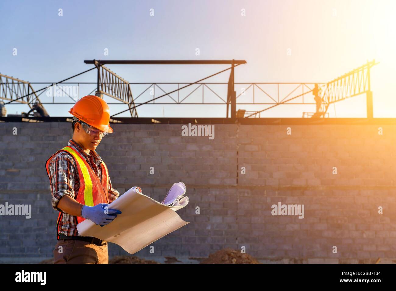 Trabajador de la construcción en un sitio de construcción que mira los planes, Tailandia Foto de stock