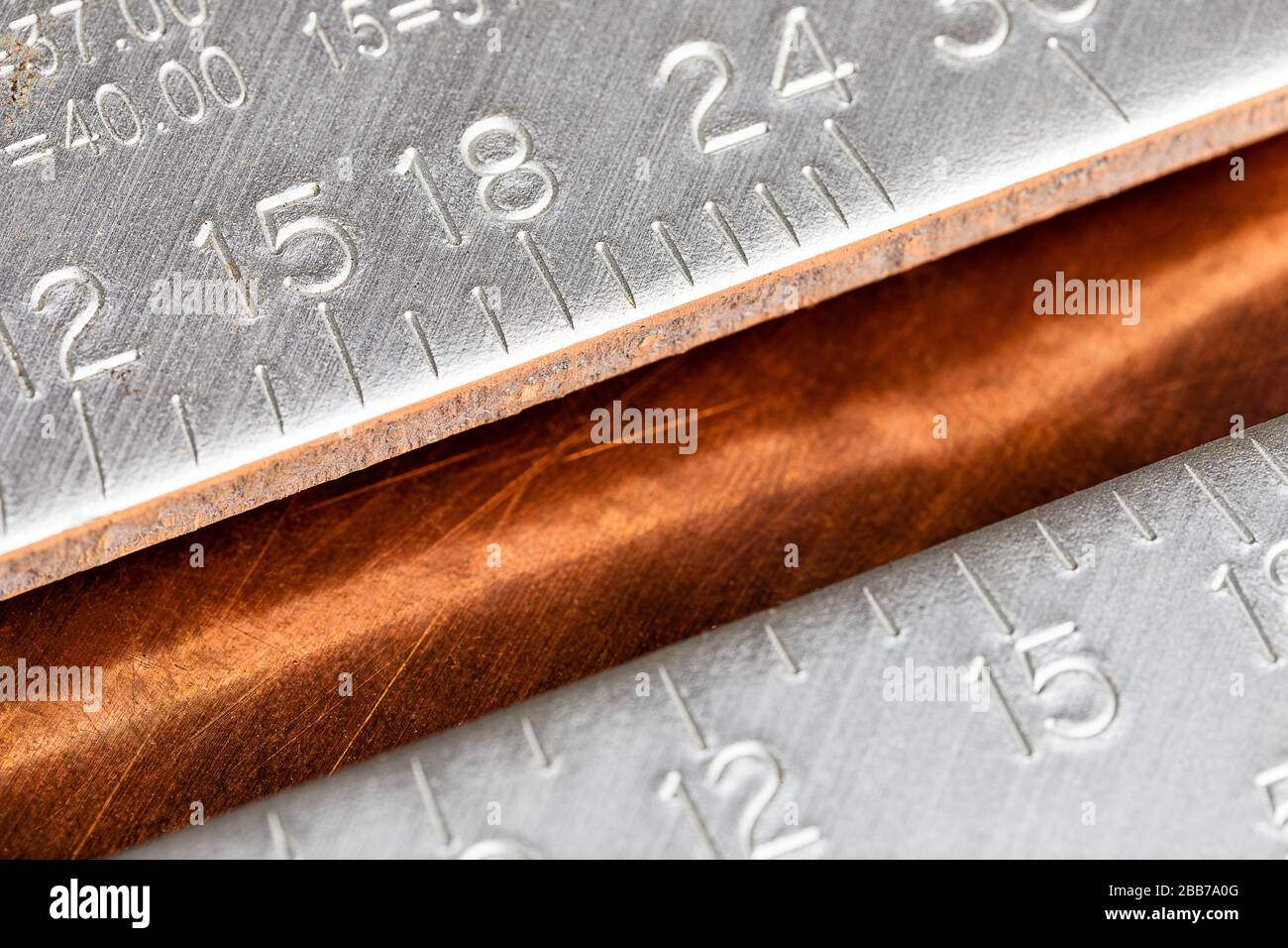 Una imagen macro de un carpintero de aluminio bien usado o de un cuadrado de techadores en una superficie de trabajo de cobre rayado y oxidado. Grabado para copiar con espacio en el cen Foto de stock