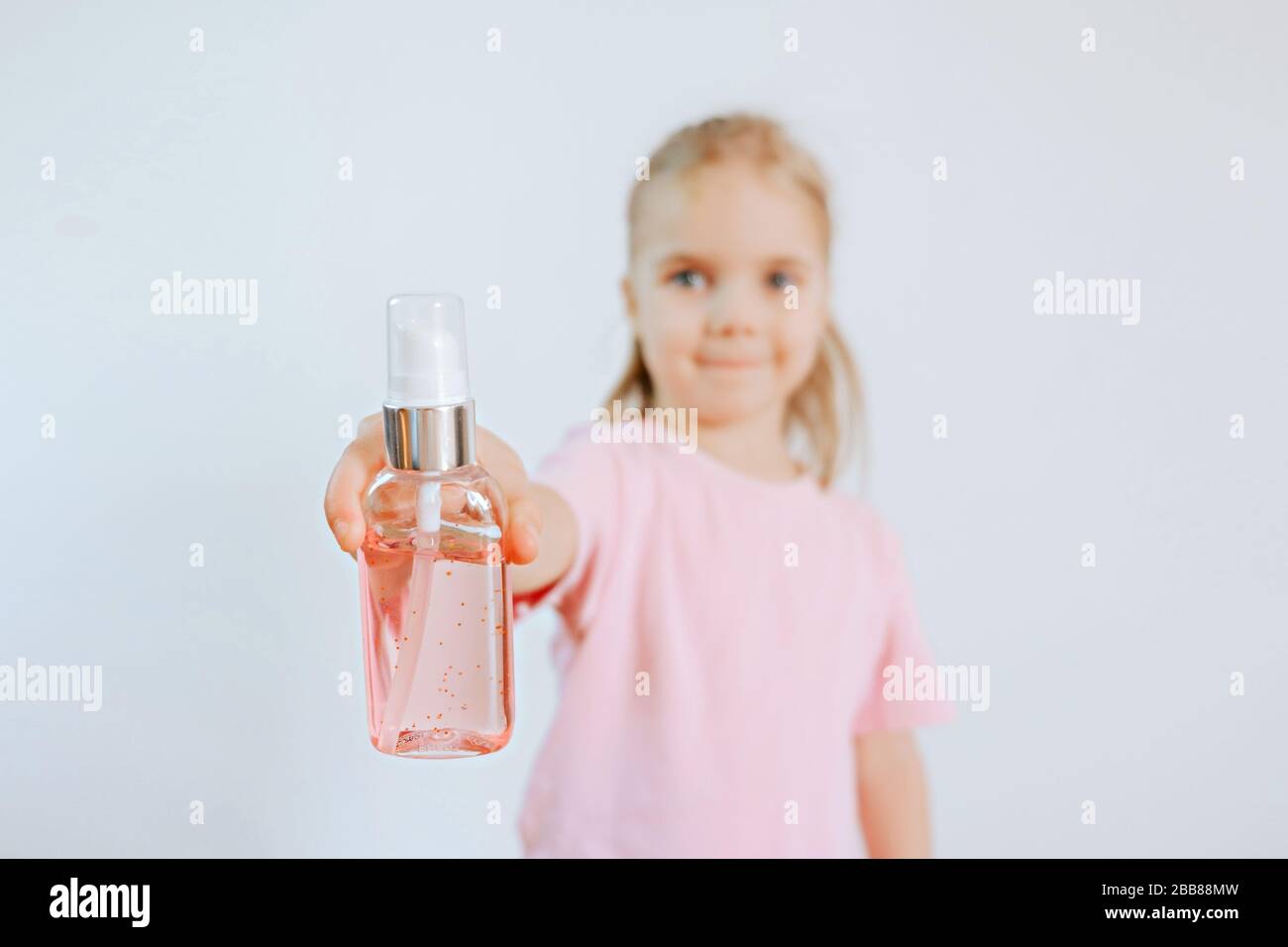 Niña sosteniendo el frasco con gel de limpieza antiséptico. Los niños usan gel de alcohol para lavarse las manos y prevenir el coronavirus Covid-19. Prevenir el virus y las bacterias Foto de stock